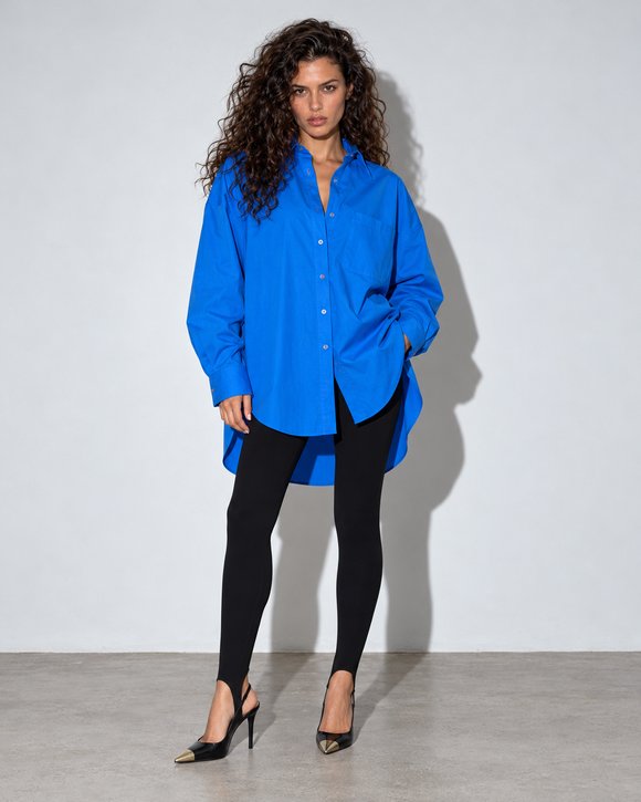 Koszula CALM Oversize Blue PATCHOULI – nowa modelka, legginsy CONFIDENT Black ze strzemionami pod stopą, czarne szpilki z metalowym noskiem, mocny flesz.