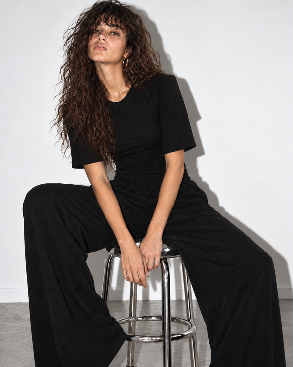 Spodnie Nonchalant Black – modelka na srebrnym stołku, T-shirt Close z rękawami do łokcia